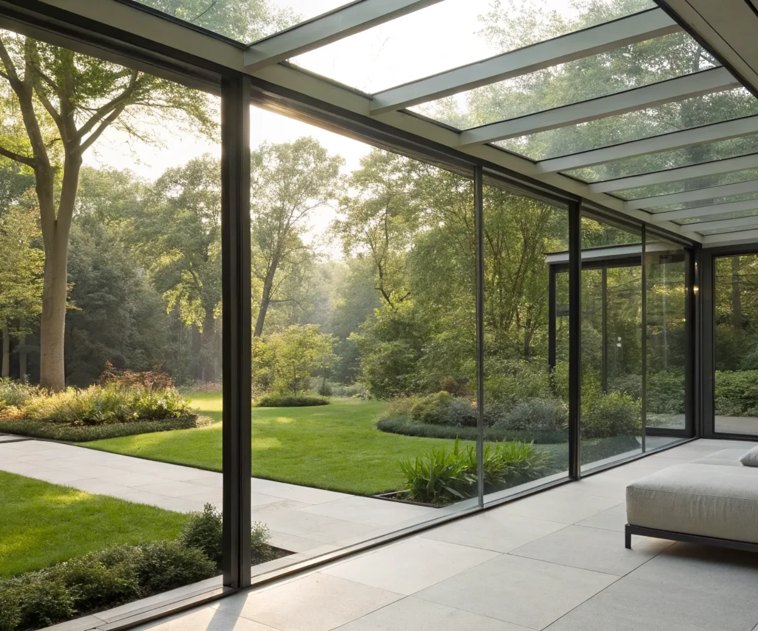 A modern steel and glass room extension with floor-to-ceiling windows and a garden view.